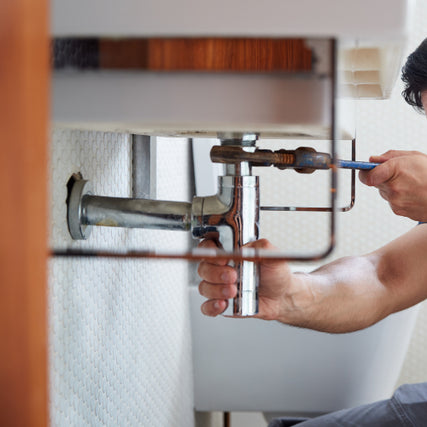 Plumbing SuppliesA plumber fixing a sink pipe uses a tool under a bathroom sink. The image focuses on the hands and plumbing, conveying focus and professionalism.