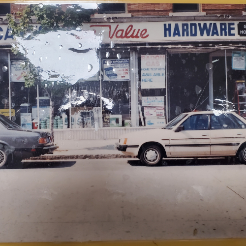 Street view of a vintage hardware store with a worn 