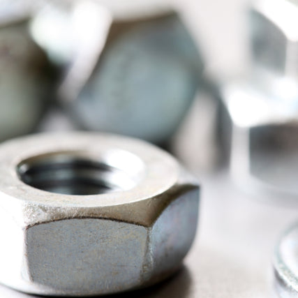 Nuts & BoltsClose-up of a shiny metal hex nut surrounded by blurred silver bolts, conveying an industrial and mechanical theme with a focus on texture.